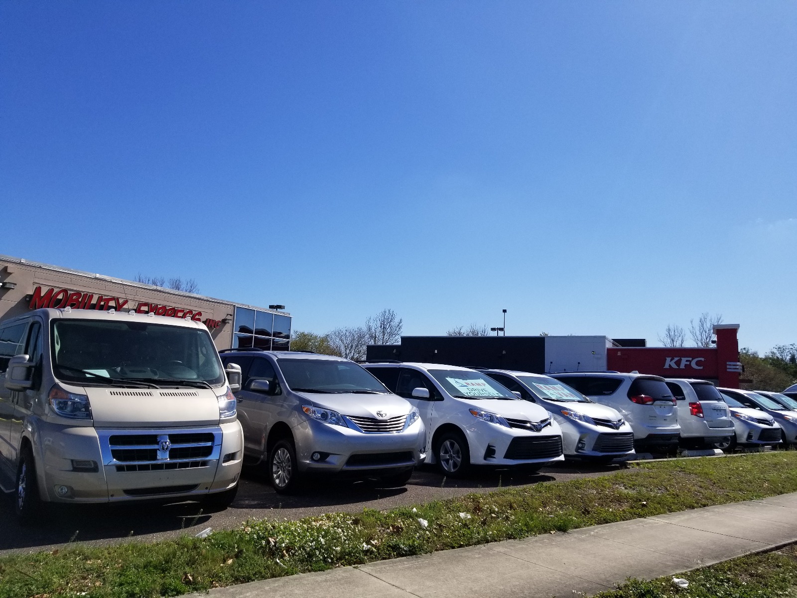 Wheelchair Vans for Sale at Mobility Express A line of handicap accessible vans parked with most facing forward, in front of a building for the wheelchair van dealer Mobility Express.
