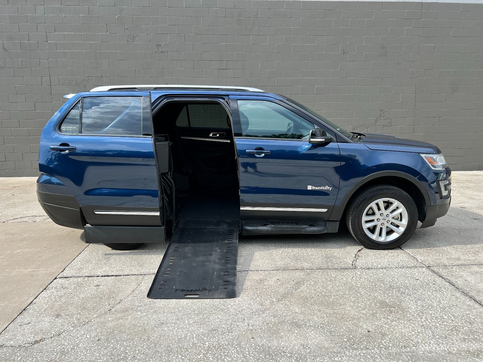 Blue Ford Explorer wheelchair accessible SUV with the ramp deployed from the open passenger side rear door.