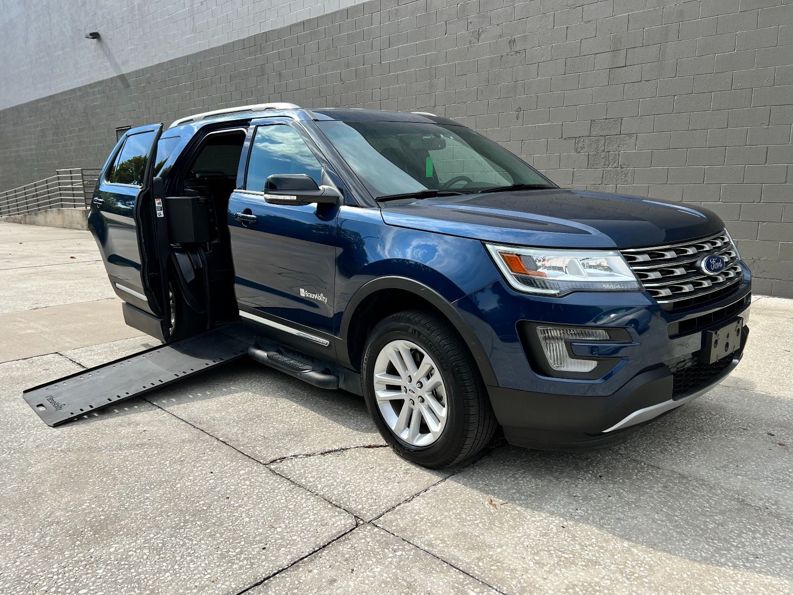 Blue 2016 Ford Explorer Wheelchair Accessible SUV with ramp deployed, as seen from passenger side, front angle.