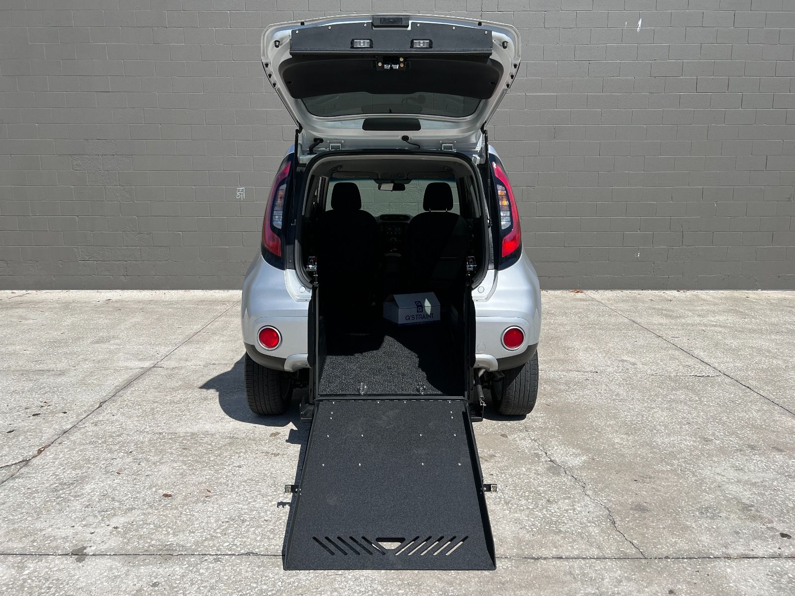 Silver Kia Soul wheelchair accessible SUV with rear entry conversion with ramp deployed from open rear hatch.